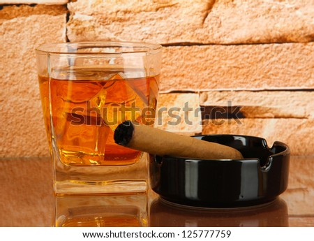 Glass of whiskey and cigar on brick wall background