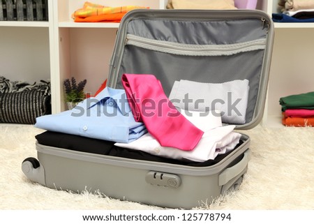 Open grey suitcase with clothing in room