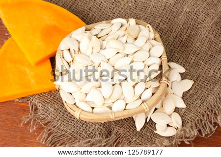 Pumpkin seeds in wicker box, on wooden background