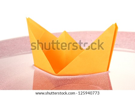 Color paper ship in water on pink plate, close-up