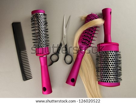 Comb brushes, hair and cutting shears, on grey background