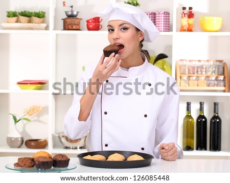 Young woman chef with cakes on dripping pan in kitchen