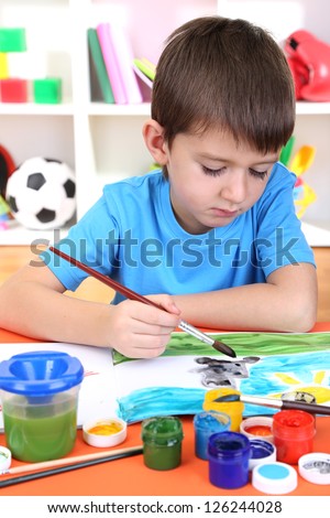 Cute little boy painting in his album