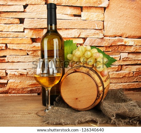 composition of wine and grapes on wooden barrel on table on brick wall background