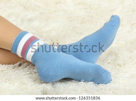 Female legs in colorful socks on  white carpet background