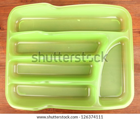 Green plastic cutlery tray on wooden table