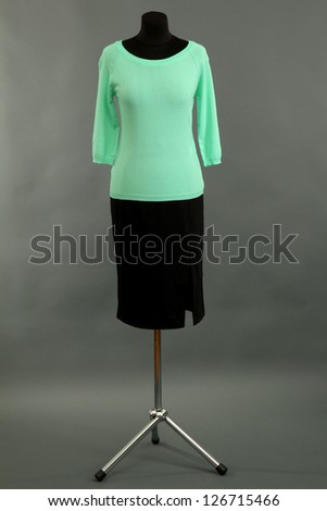 Turquoise blouse and black skirt on mannequin on grey background