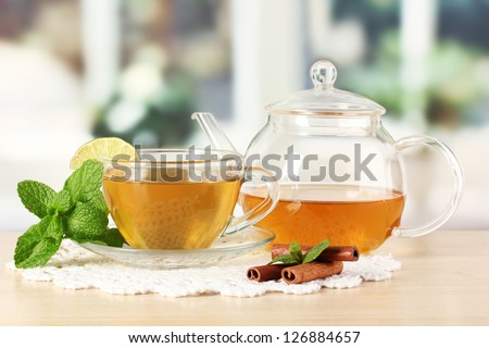 Cup of tea with mint,lime and cinnamon on table in room