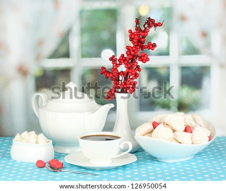 Beautiful white dinner service with an air meringues on blue tablecloth on window background