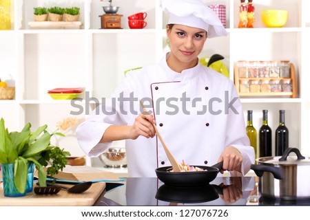 Young woman chef cooking in kitchen
