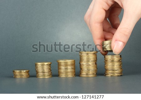 Hand holding coins on grey background