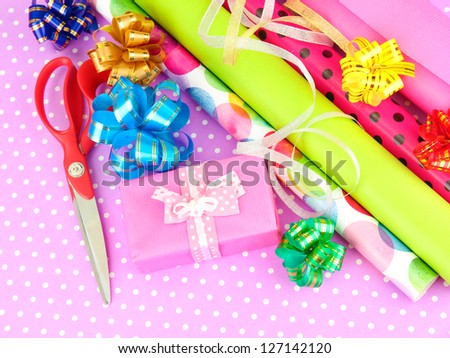 Rolls of Christmas wrapping paper with ribbons, bows on color background