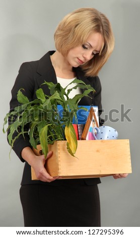 Young beautiful woman fired from her job on grey background