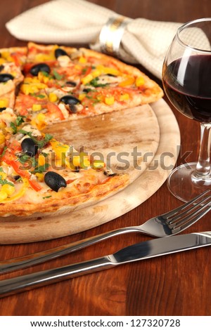 Tasty pizza with wine on wooden table close-up