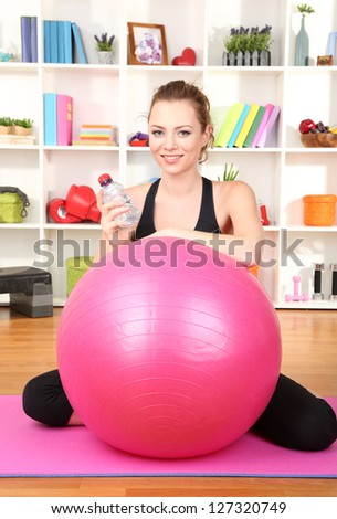 Young woman with gym ball at home