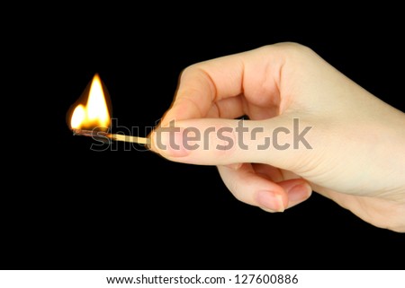 Burning match in female hand, isolated on black