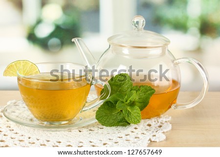 Cup of tea with mint and lime on table in room