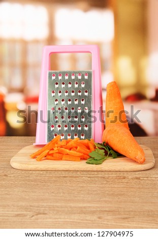 carrots with grater on cutting board on table in kitchen