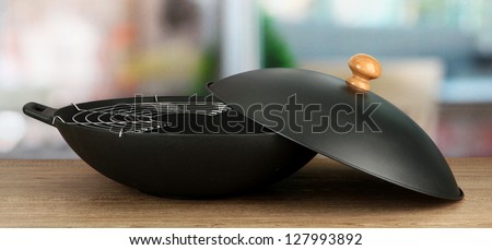 Black wok pan on kitchen table, close up