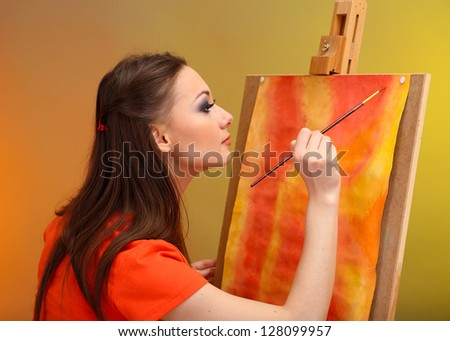beautiful young woman painter at work, on bright color background