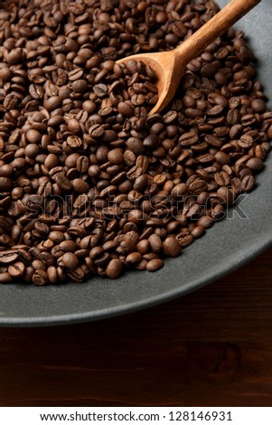Black wok pan with coffee beans on wooden table, close up