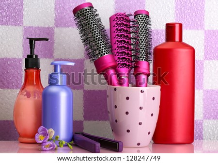 Hair brushes, hair straighteners and cosmetic bottles in bathroom