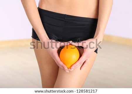 Beautiful female figure with orange on light background
