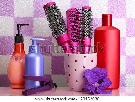 Hair brushes, hair straighteners and cosmetic bottles in bathroom