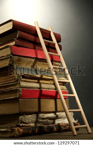 Old books and wooden ladder, on grey background