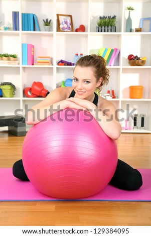 Young woman with gym ball at home