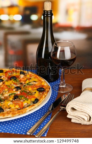 Tasty pizza with wine on wooden table on room background close-up