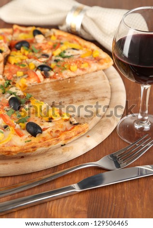 Tasty pizza with wine on wooden table close-up