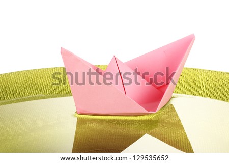 Color paper ship in water on green plate, close-up