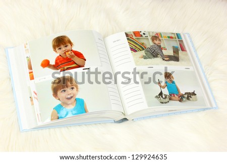 Open photo album with pictures on white carpet