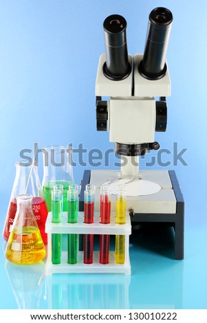 Test tubes with colorful liquids and microscope on blue background