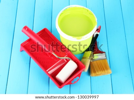 Set for painting: paint pot, brushes, paint-roller on blue wooden table