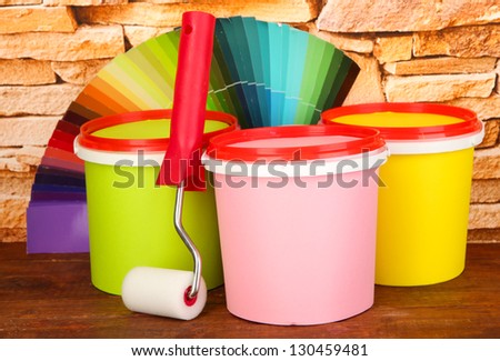Set for painting: paint pots, paint-roller, palette of colors on stone wall background