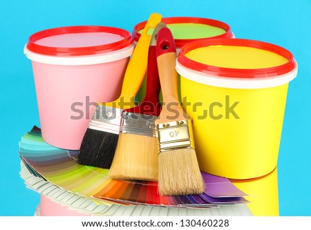 Set for painting: paint pots, brushes, palette of colors on blue background