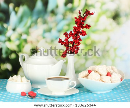Beautiful white dinner service with an air meringues on blue tablecloth on natural background