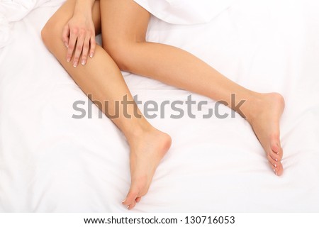 Young woman lies on her bed with long legs