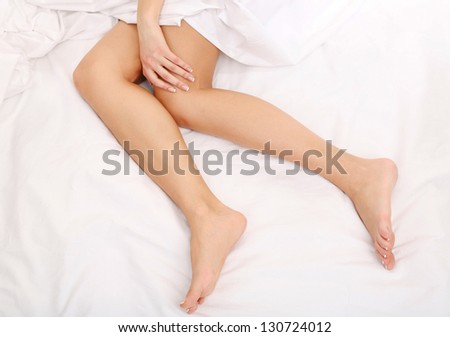 Young woman lies on her bed with long legs