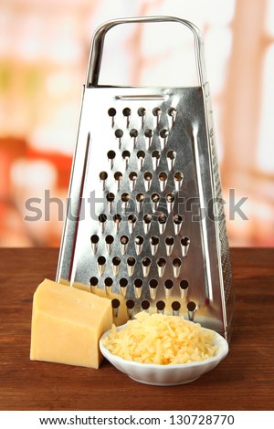 Metal grater and cheese, on bright background