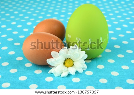 Green egg timer and eggs, on color background