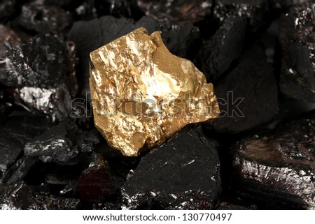 Golden nugget on coals background close-up