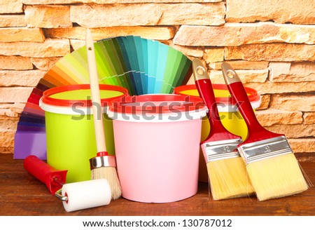 Set for painting: paint pots, brushes, paint-roller, palette of colors on stone wall background