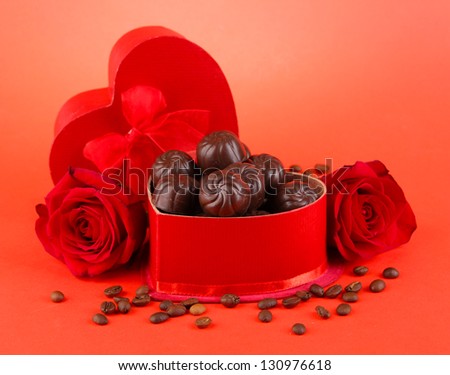 Chocolate candies in gift box, on red background