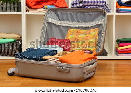 Open grey suitcase with clothing in room