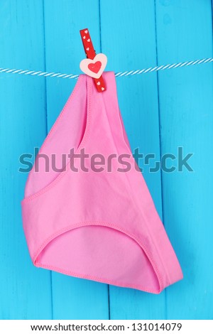 Womans panties hanging on a clothesline, on blue wooden background