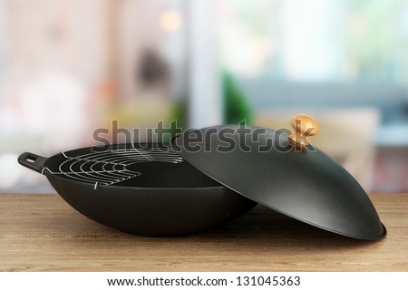 Black wok pan on kitchen table, close up