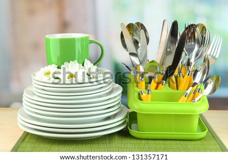 Plates, forks, knives, spoons and other kitchen utensil on bamboo mat, on bright background